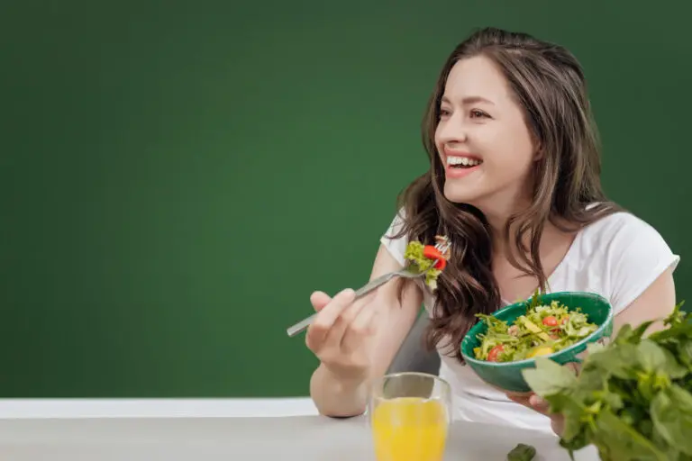 mujer-joven-comiendo-comida-saludable-sentada-hermoso-interior-pared-verde-fondo (1)